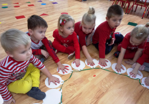 Dzieci odbijają rękę pomalowaną farbą na papierowej bombce
